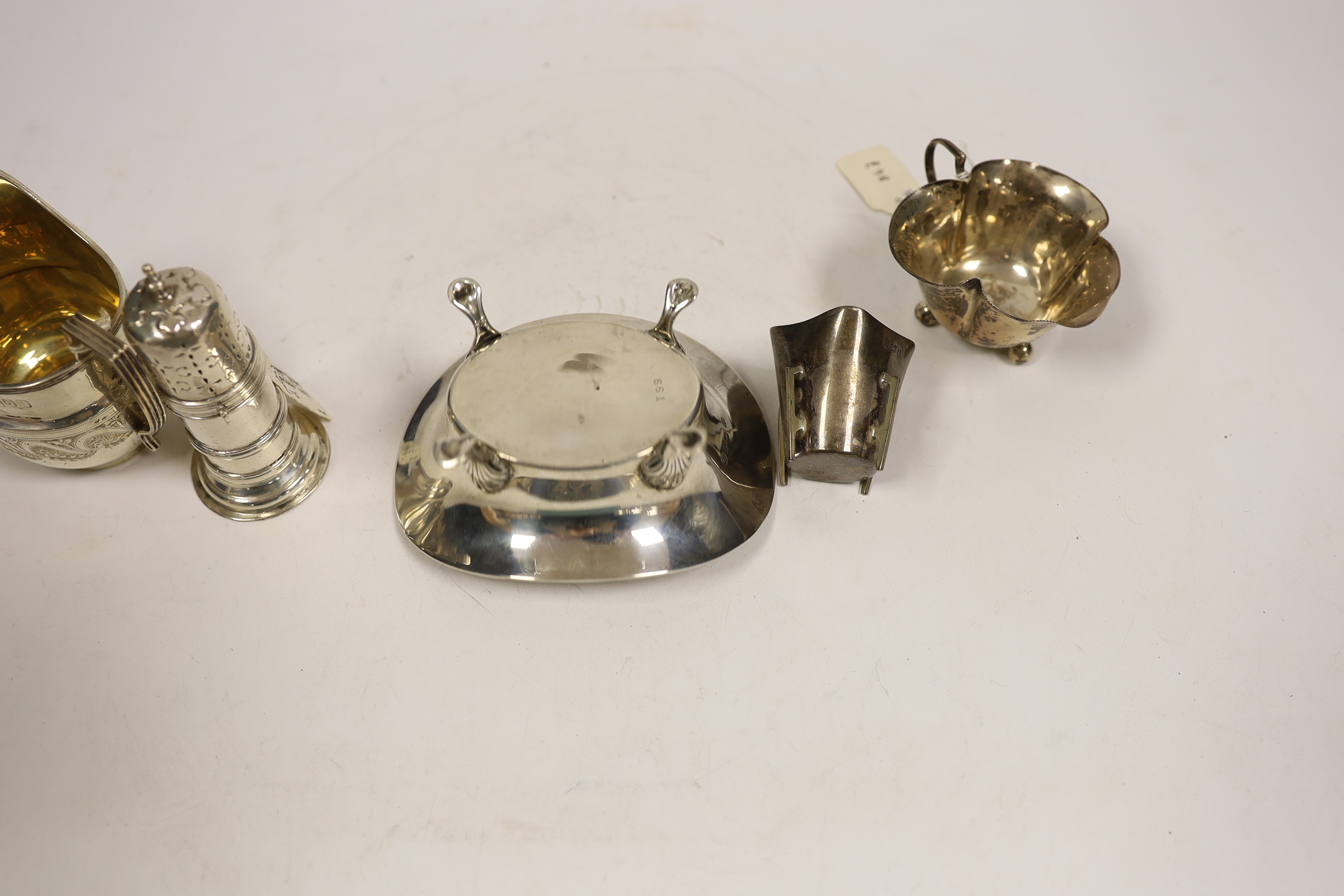 Small silverware, consisting:- a late Victorian helmet shaped cream jug, 1896; a George V oval sugar bowl, a late Victorian lighthouse sugar caster, 91mm, an Edwardian silver cream jug, 1908 and a silver tot.